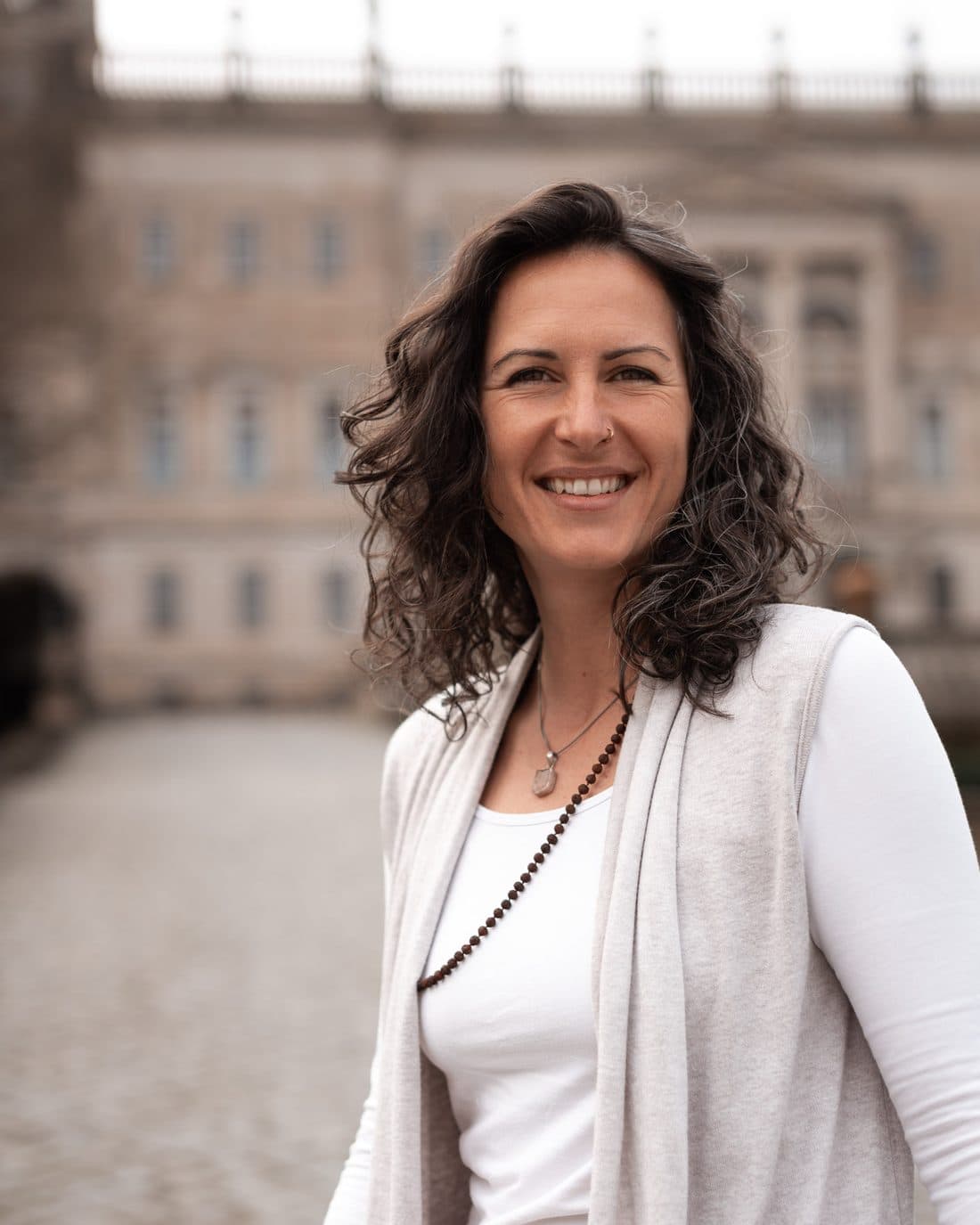 Romy Schwarz lächelt in die Kamera, hinter ihr ein helles Schloss